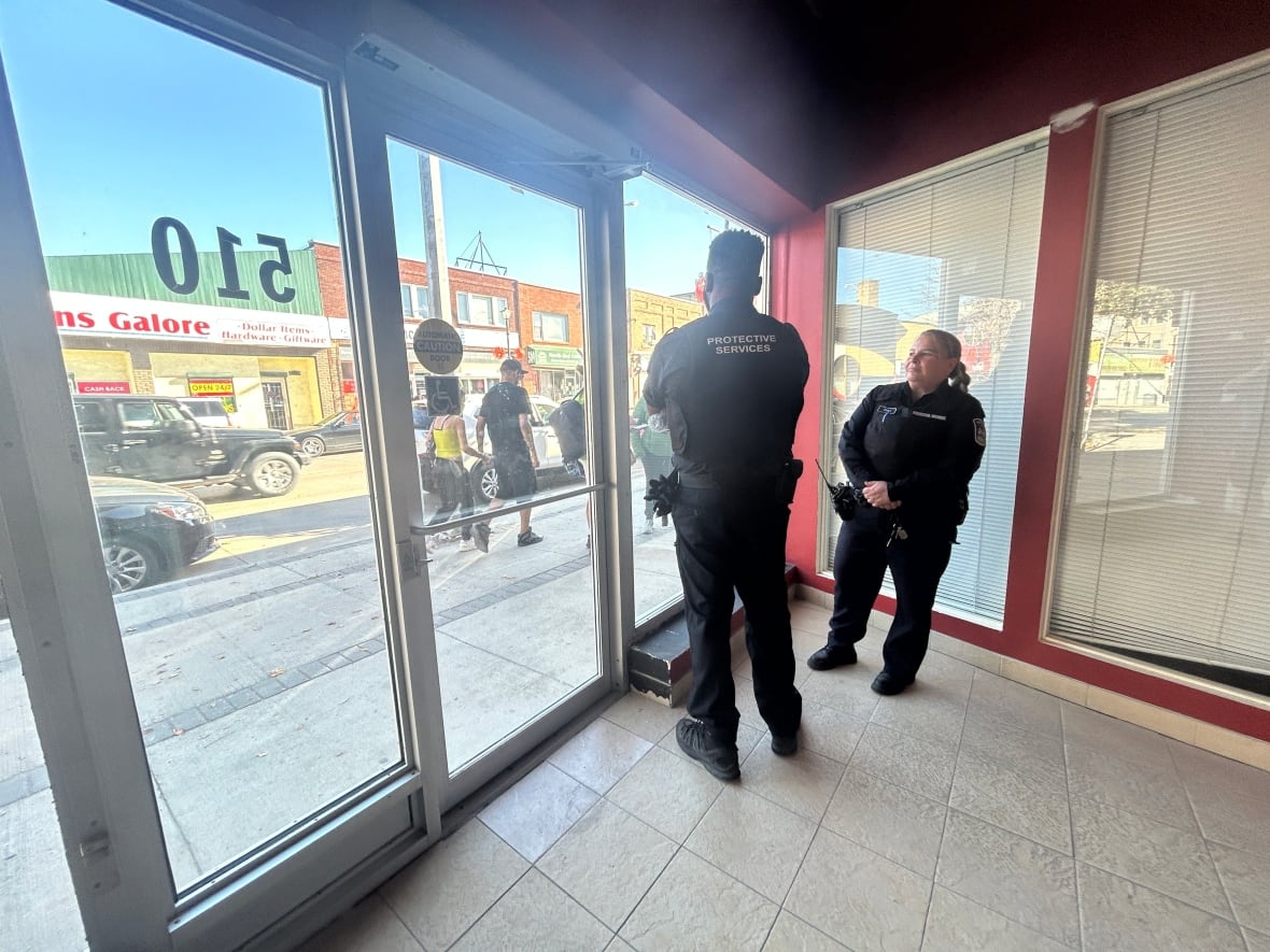 Two guards stand watch inside the entrance of a building where politicians made a funding announcement.