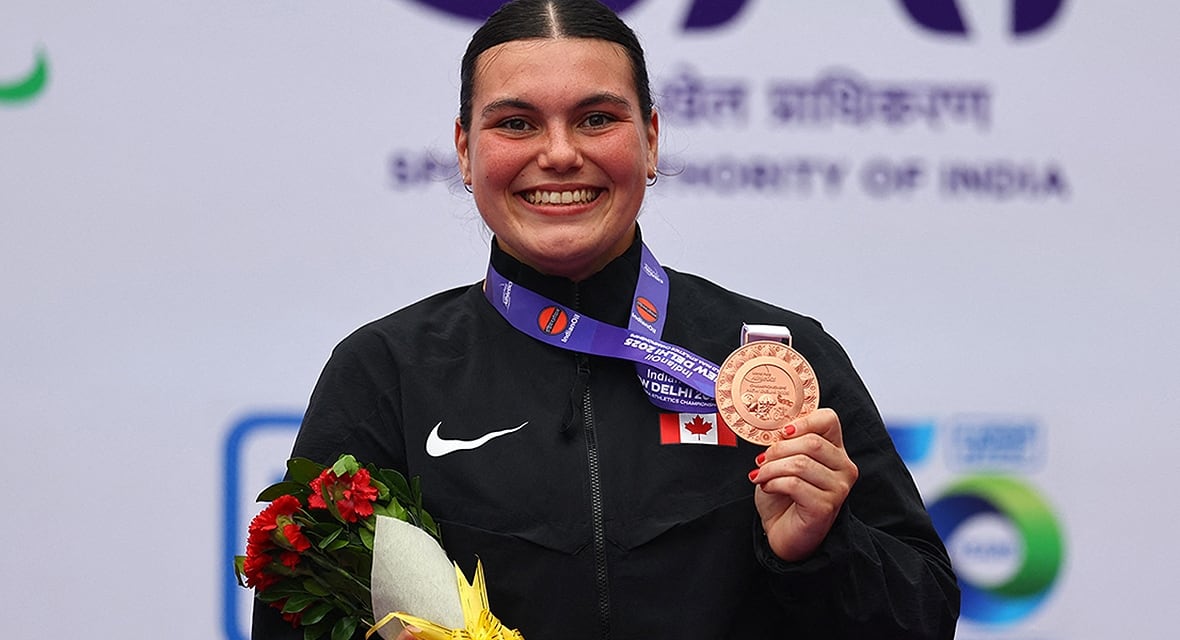 Promieniejąca kanadyjska lekkoatletka Katie Pegg świętuje zdobycie medalu, trzymając w lewej ręce brązowy medal po finale pchnięcia kulą F46 kobiet podczas mistrzostw świata w lekkoatletyce osób niepełnosprawnych 2 października 2025 r. w Nowym Delhi w Indiach.
