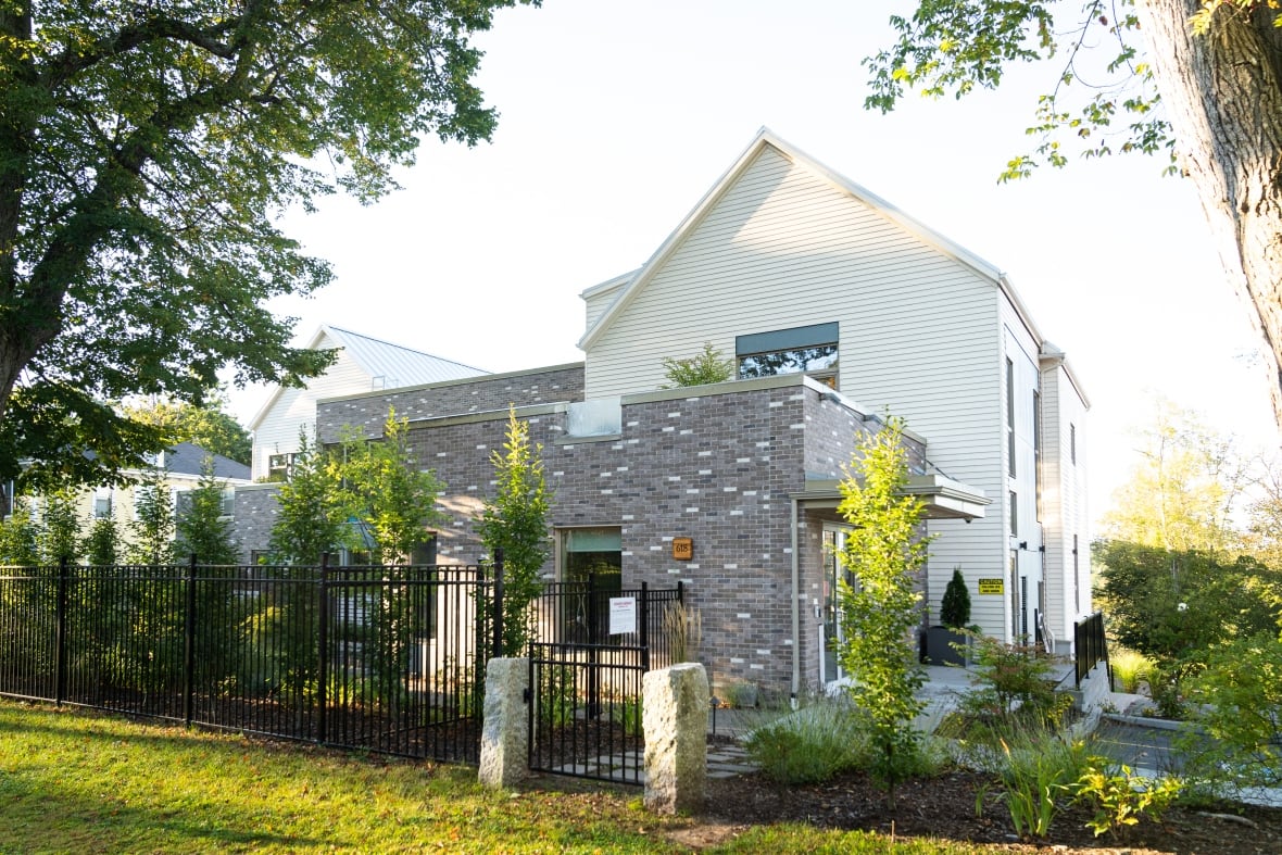 Exterior of a brick and shingle building surrounded by a garden.