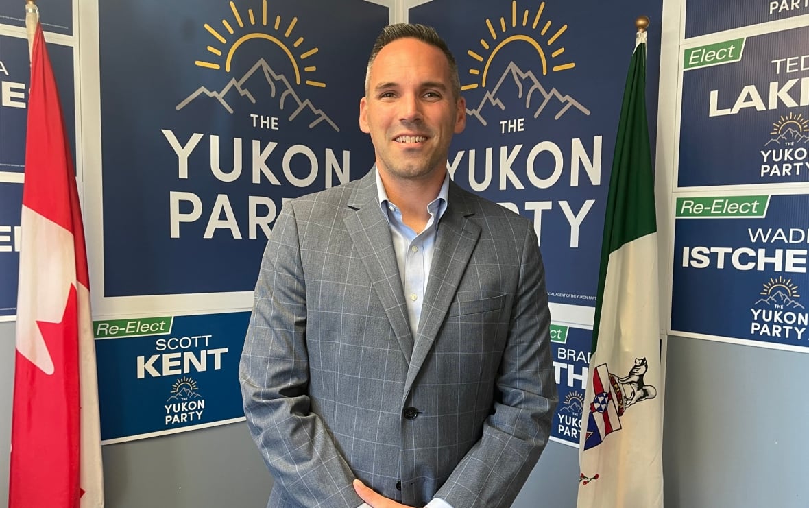 A man stands in a room in front of some Yukon Party election signs.