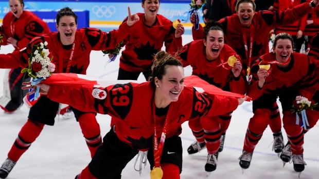 The Canadian women's hockey team celebrates winning Olympic gold on the ice.