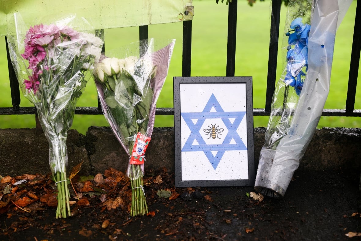 Flower bouquets are placed in an iron fence.