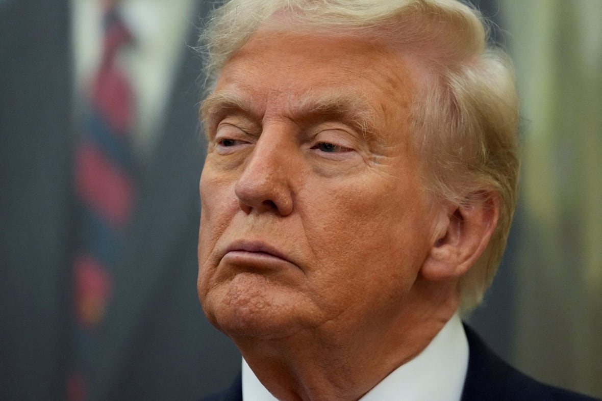 U.S. President Donald Trump looks on.