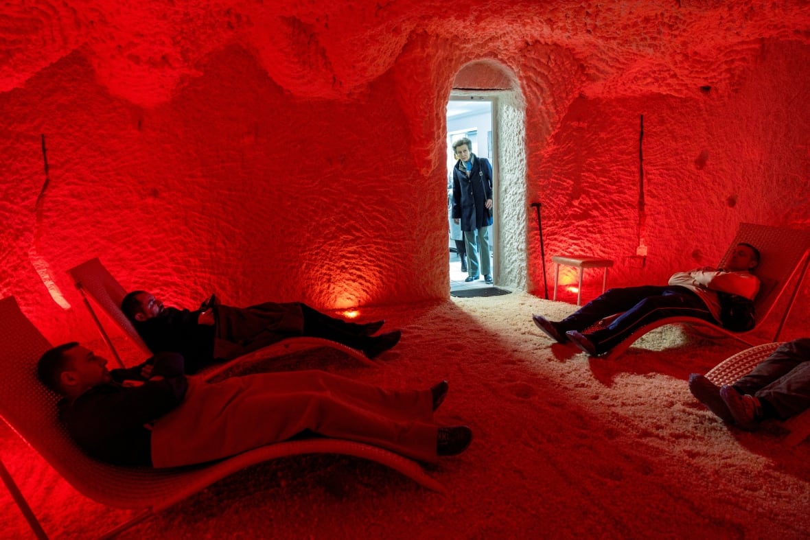 A person looks through a door into a room with red walls where people are relaxing in lounging chairs.