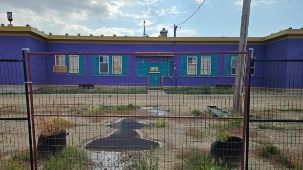 A fence outside of a purple-coloured building.