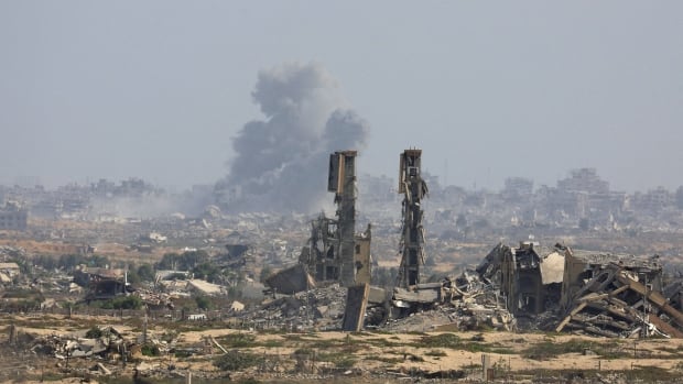Smoke rises amid rubble from afar.