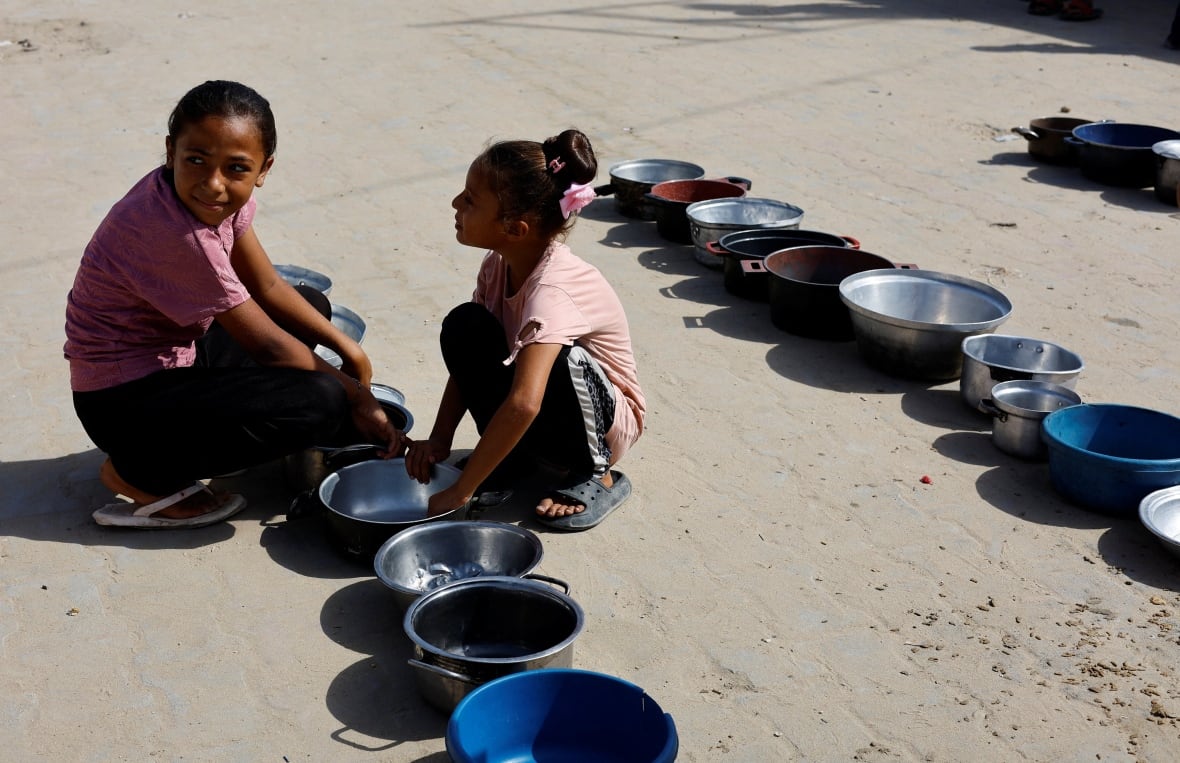 Two small girls sit next to the empty vessels.