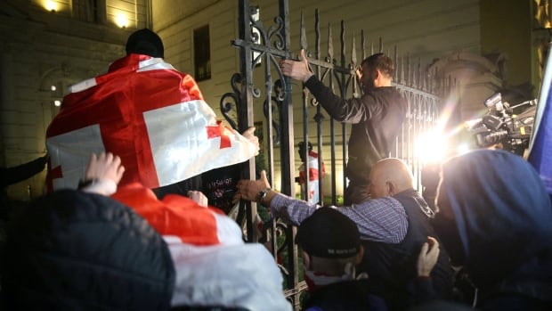 Protesters attempt to climb over a fence.