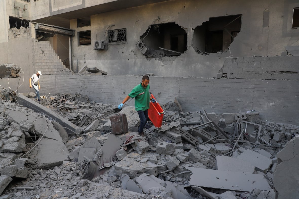 A paramedic carrying a stretcher walks amid rubble.