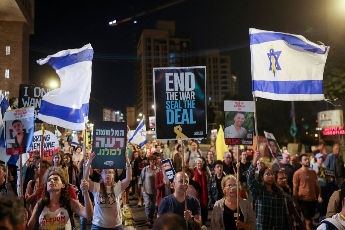 Protesters hold up signs and flags during a rally.