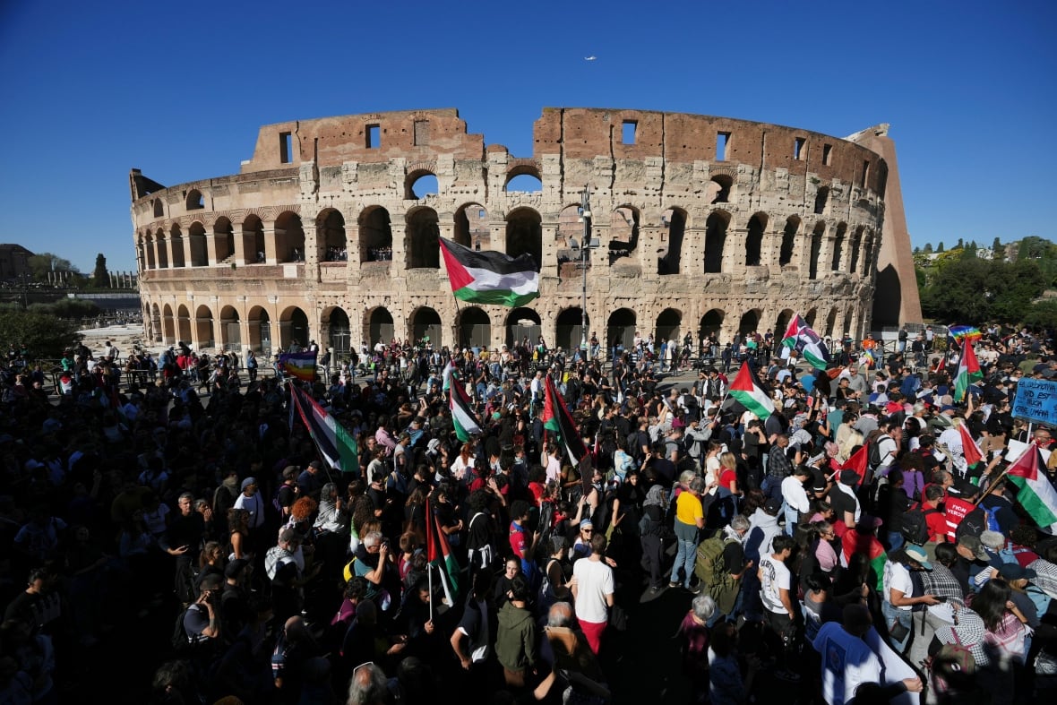 Protesters march past an ancient Roman building.