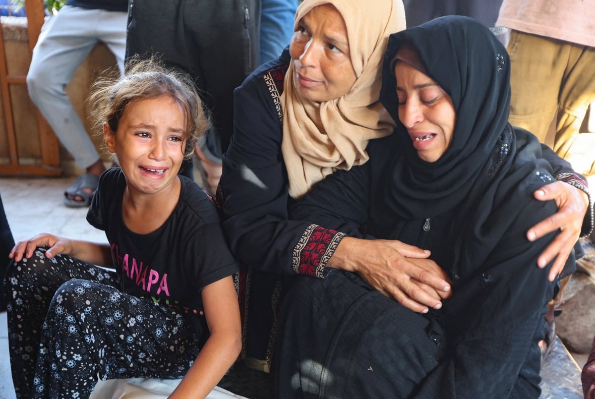 Two women and a girl cry and console themselves.