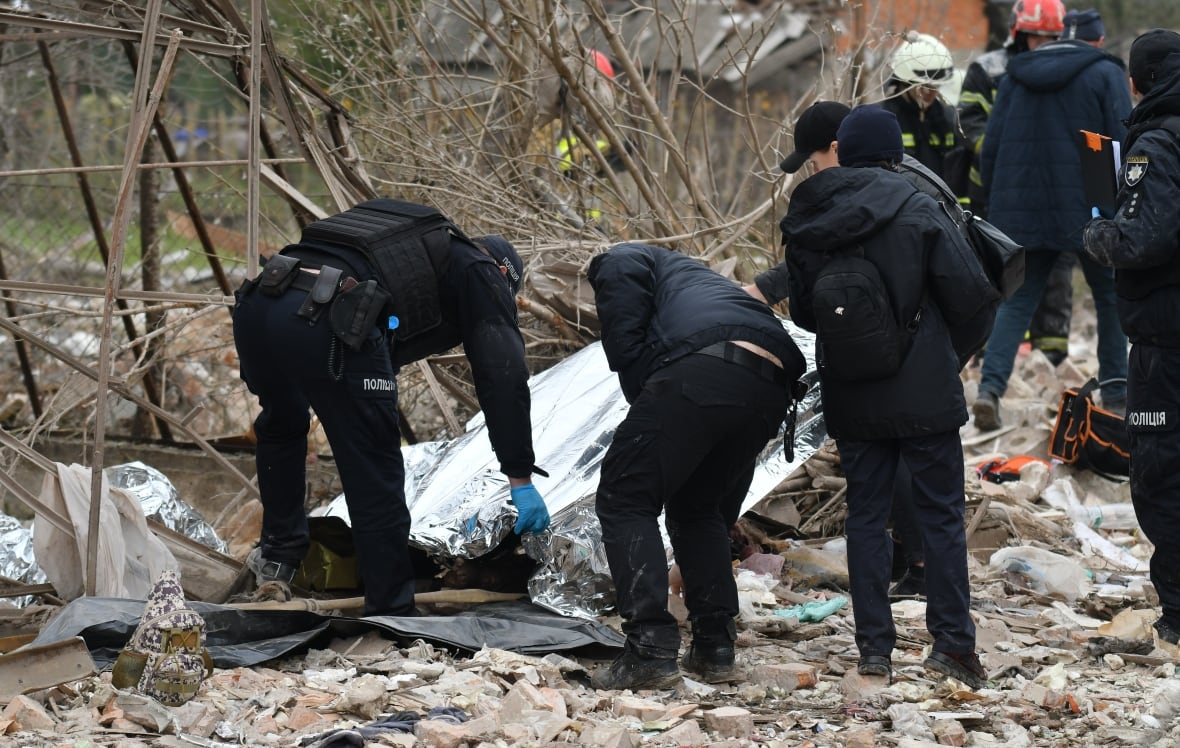 The police tend to the aluminum sheet placed on the debris.