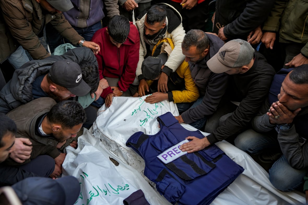 The mourners gather around the bodies of the deceased coated with a white cloth.
