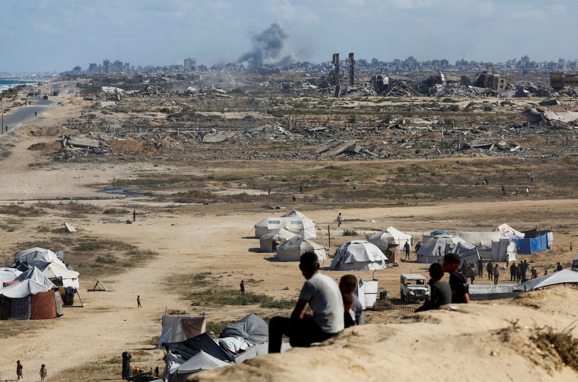 People sit over the hill see that smoke rises above a destroyed city.