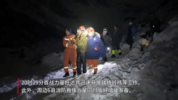Several people are shown in a nighttime photo outdoors, wearing winter clothing. Some have helmets with flashlights on top of them.