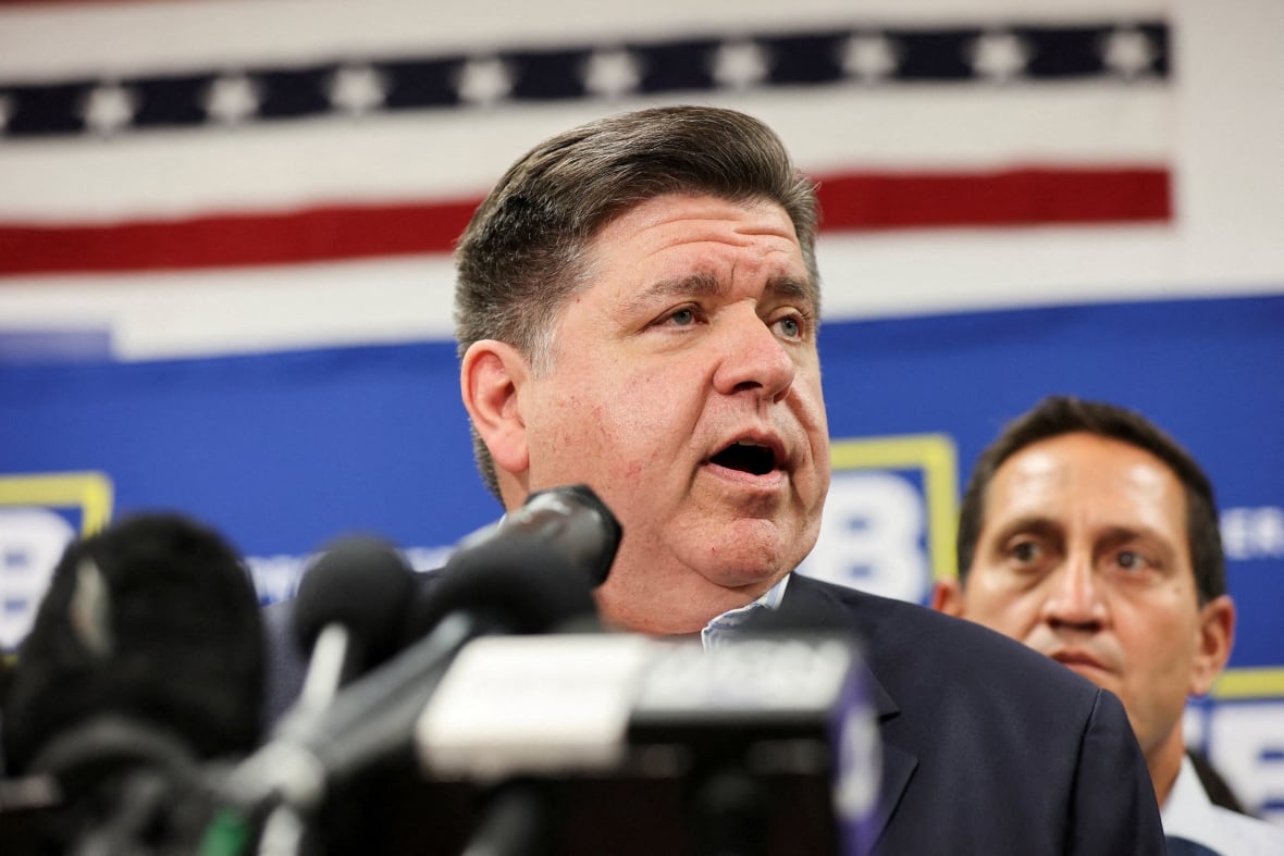 A man wearing a dark suit speaks on a podium