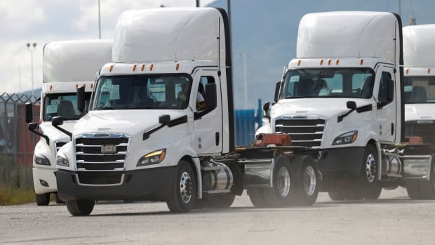 Several white heavy duty trucks are shown.