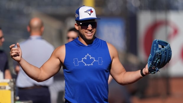 A baseball player spreads his arms wide.