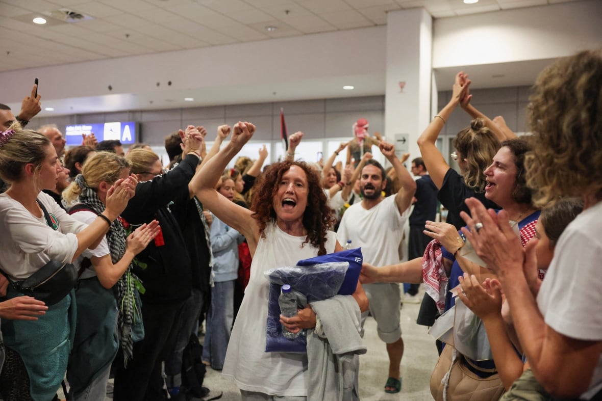 People are walking through a crowd of spectators, chanting with their arms raising 
