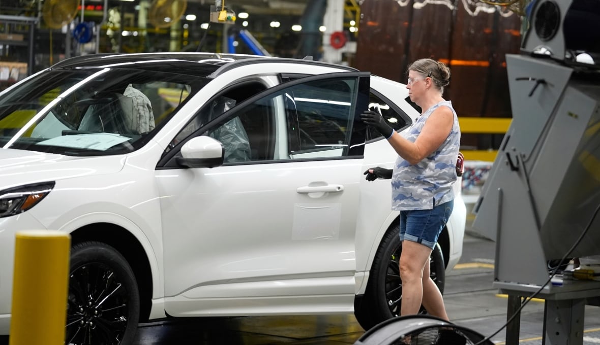 A car member is working on a car on the assembly line. 