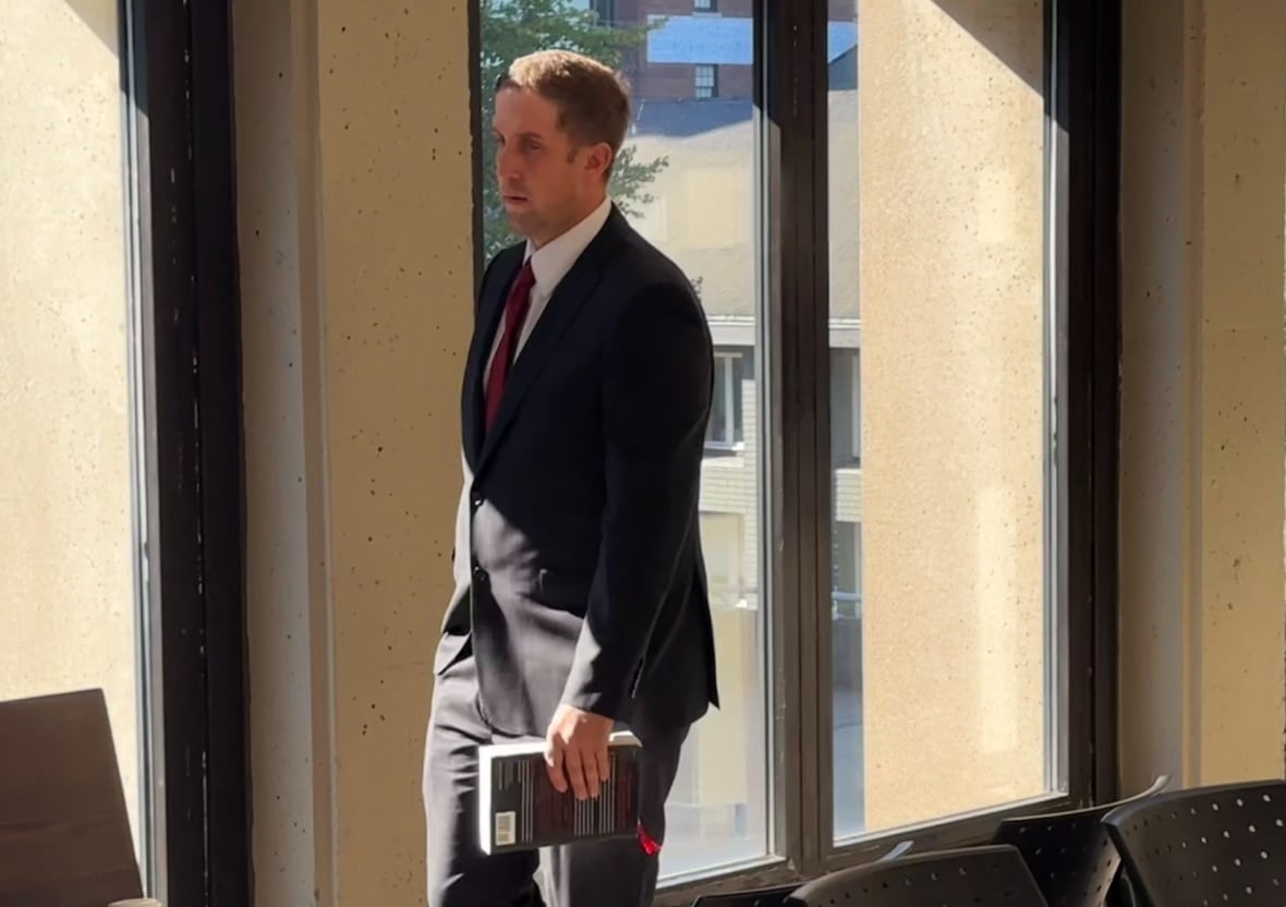 A man with a suit and a book in his hand is shown walking.
