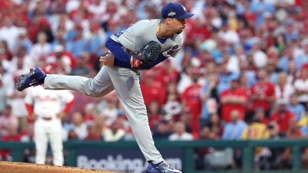 A baseball pitcher is shown leaning forward off the mound after delivering a pitch.