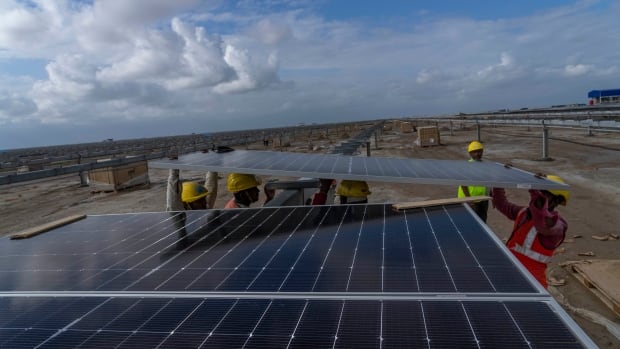 Workers install solar panels at the under-construction Adani Green Energy Limited's Renewable Energy Park in the salt desert of Karim Shahi village, near Khavda, Bhuj district near the India-Pakistan border in the western state of Gujarat, India, Thursday, Sept. 21, 2023. Led by new solar power, the world added renewable energy at breakneck speed in 2023, in an effort to turn away from fossil fuels to stave off severe Earth warming and its effects. (AP Photo/Rafiq Maqbool)