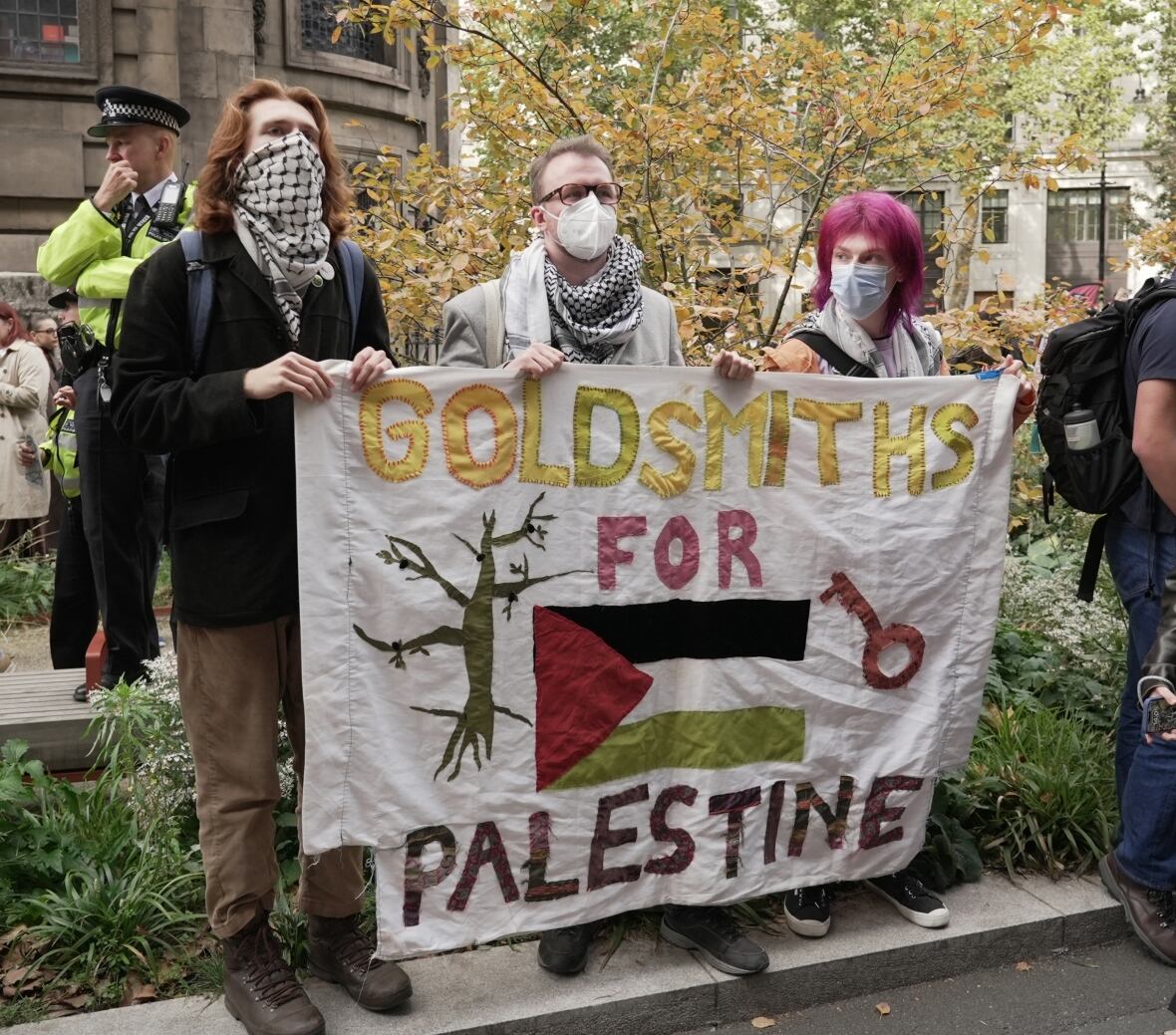 People stand at the back of a crowd of people in front of the King's College College in London on Tuesday before a student march led by students, in protest against the Israeli war in Gaza. 