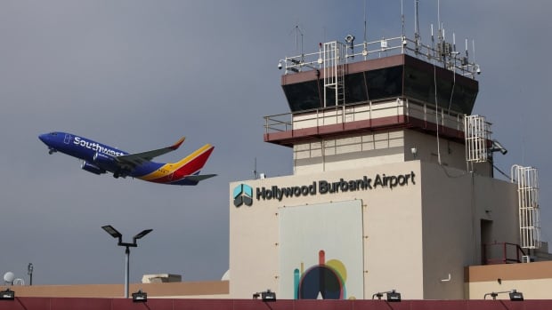 A plane takes off next to a building that  says Hollywood Burbank Airport