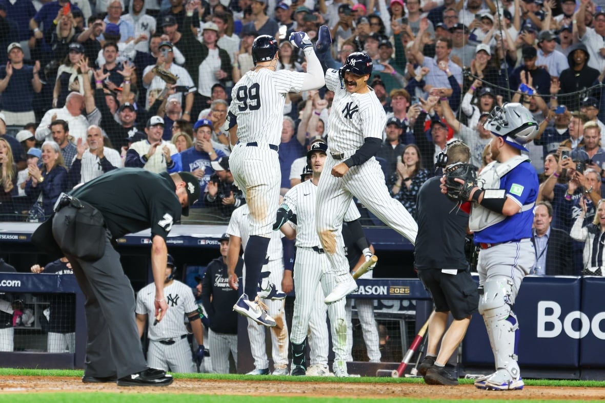 Players in white striped uniforms jump and celebrate together at a baseball stadium