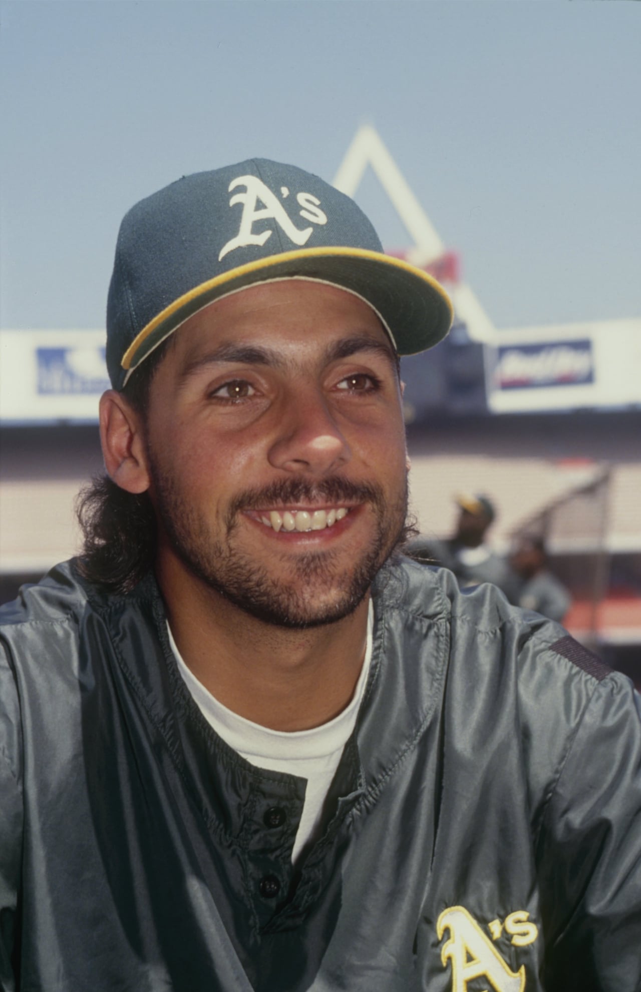 A baseball player smiles as he looks away from the camera.