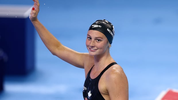 Toronto's Summer McIntosh celebrates after winning gold and setting a new championship record of 4:25.78 in the women's 400-metre individual medley at the World Aquatics Championships in Singapore on Aug. 3. A female swimmer smiles while waving with her right hand as she stands outside the pool.