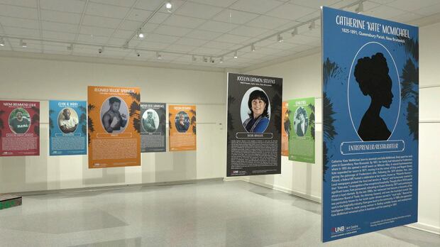 An exhibit at UNB Arts Centre in Fredericton for the month of February features the stories of Black New Brunswickers who have made significant contributions to the community and yet, in many cases, have not received recognition. Placards containing biographies of Black New Brunswickers hang from the ceiling in a white room.