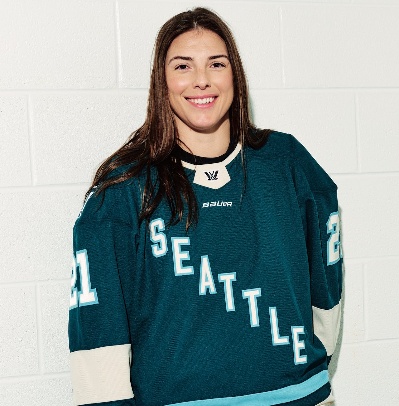 A woman wears a hockey jersey with Seattle on the front.