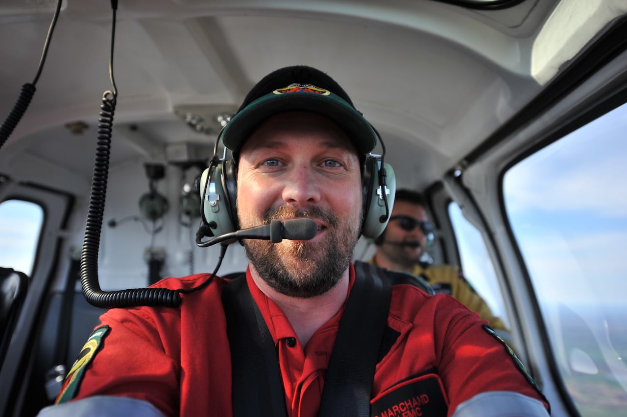 A person is seen sitting in an aircraft, wearing a headset and a baseball cap.