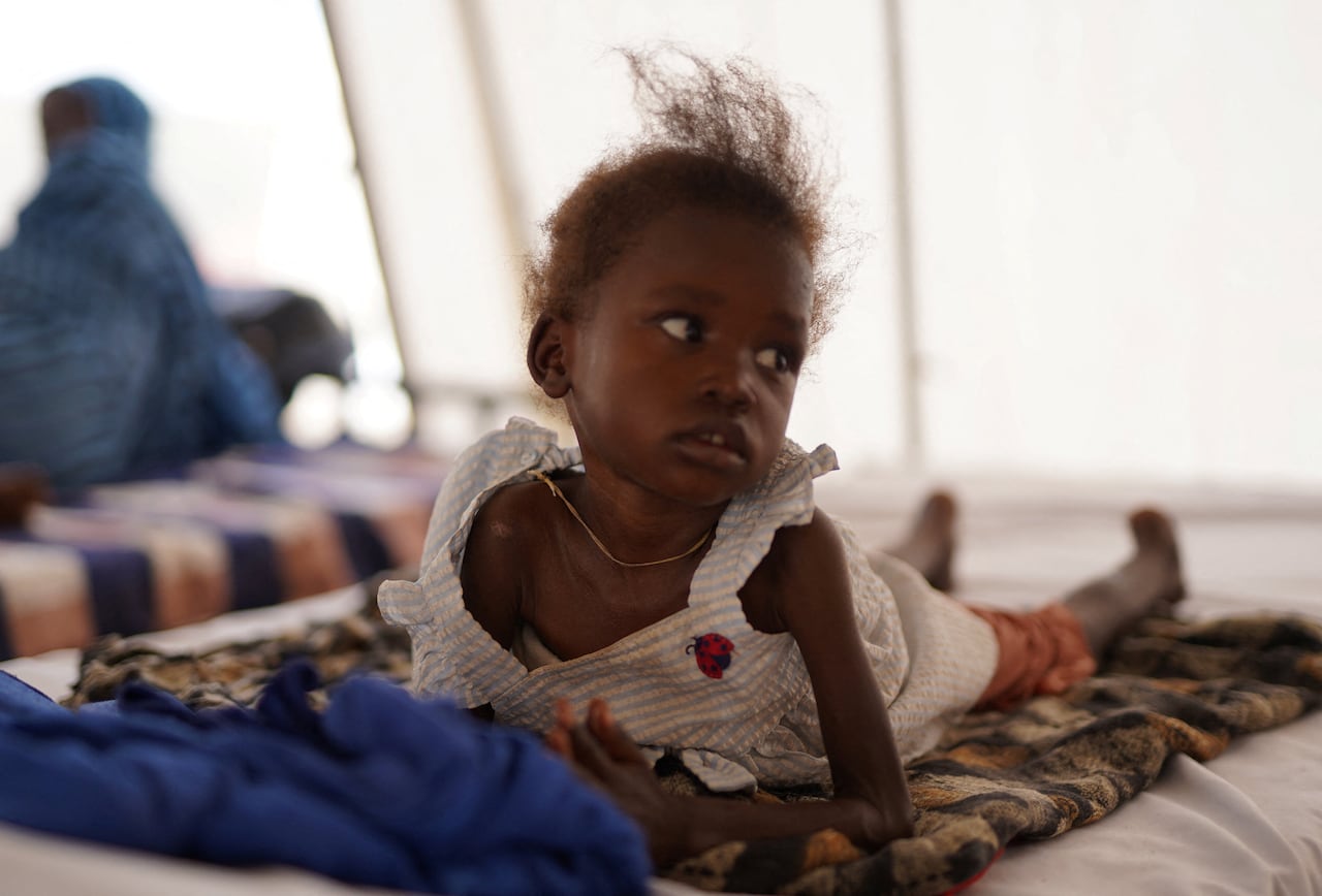 An injured and displaced Sudanese girl lies inside a makeshift clinic.