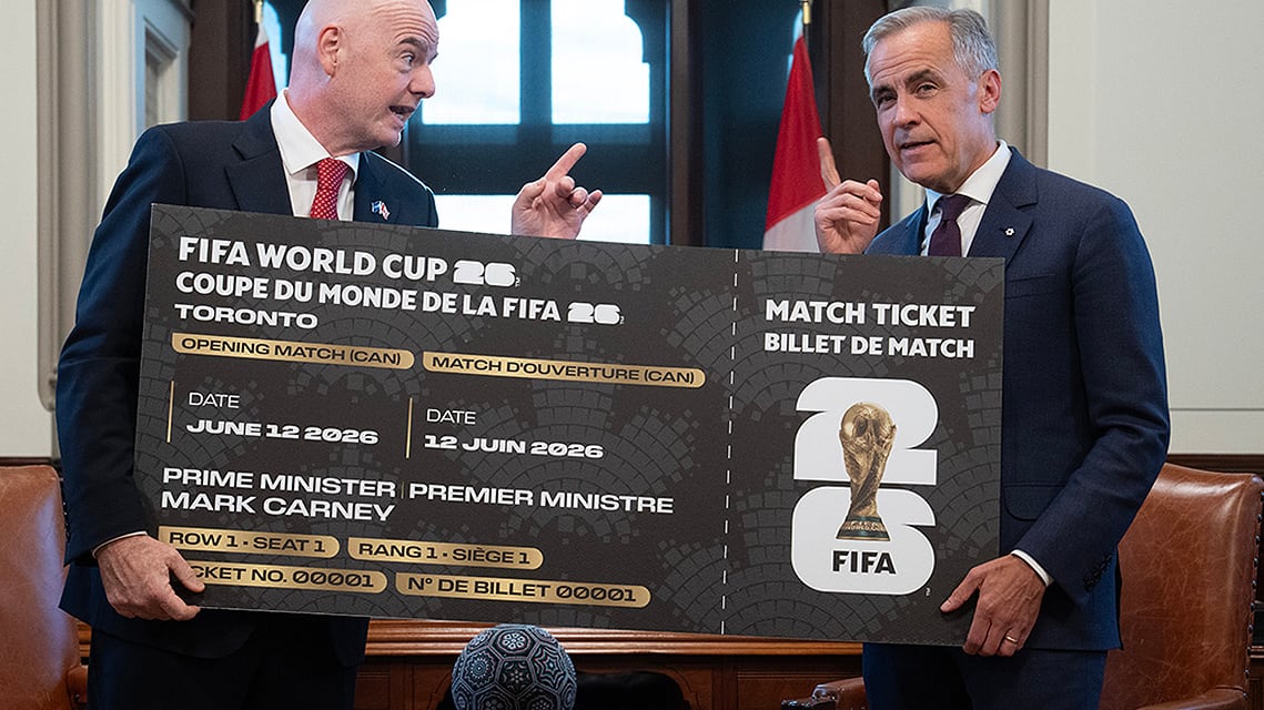   Canadian Prime Minister Mark Carney, right, is presented with a novelty World Cup ticket by FIFA president Gianni Infantino at the start of a meeting in his office on Parliament Hill in Ottawa on October 10, 2025.