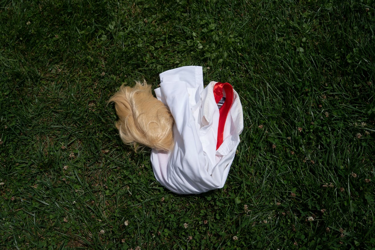 A wig, a tie and a shirt are seen on the grass.