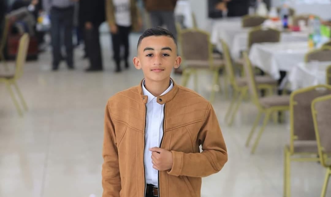 A boy stands and smiles.