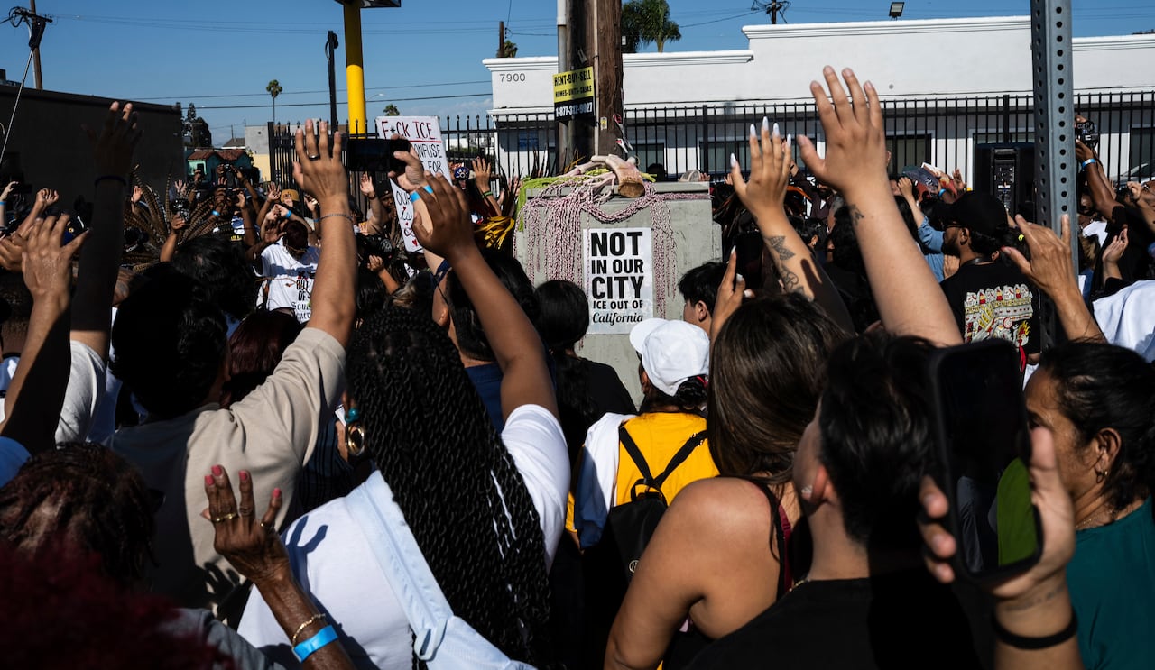 Dozens of Los Angelenos raise their hands in prayer while protesting immigration raids in their communities.