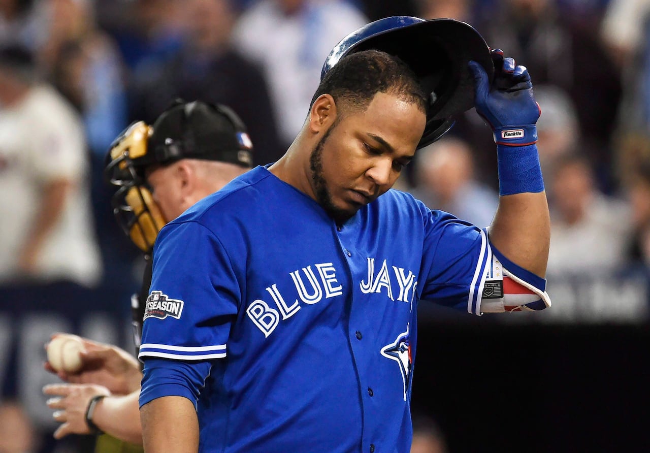 A baseball player looks down, while pulling his batting helmet off