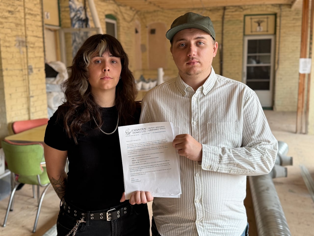 A couple poses with a notice they received from the property management company on their building