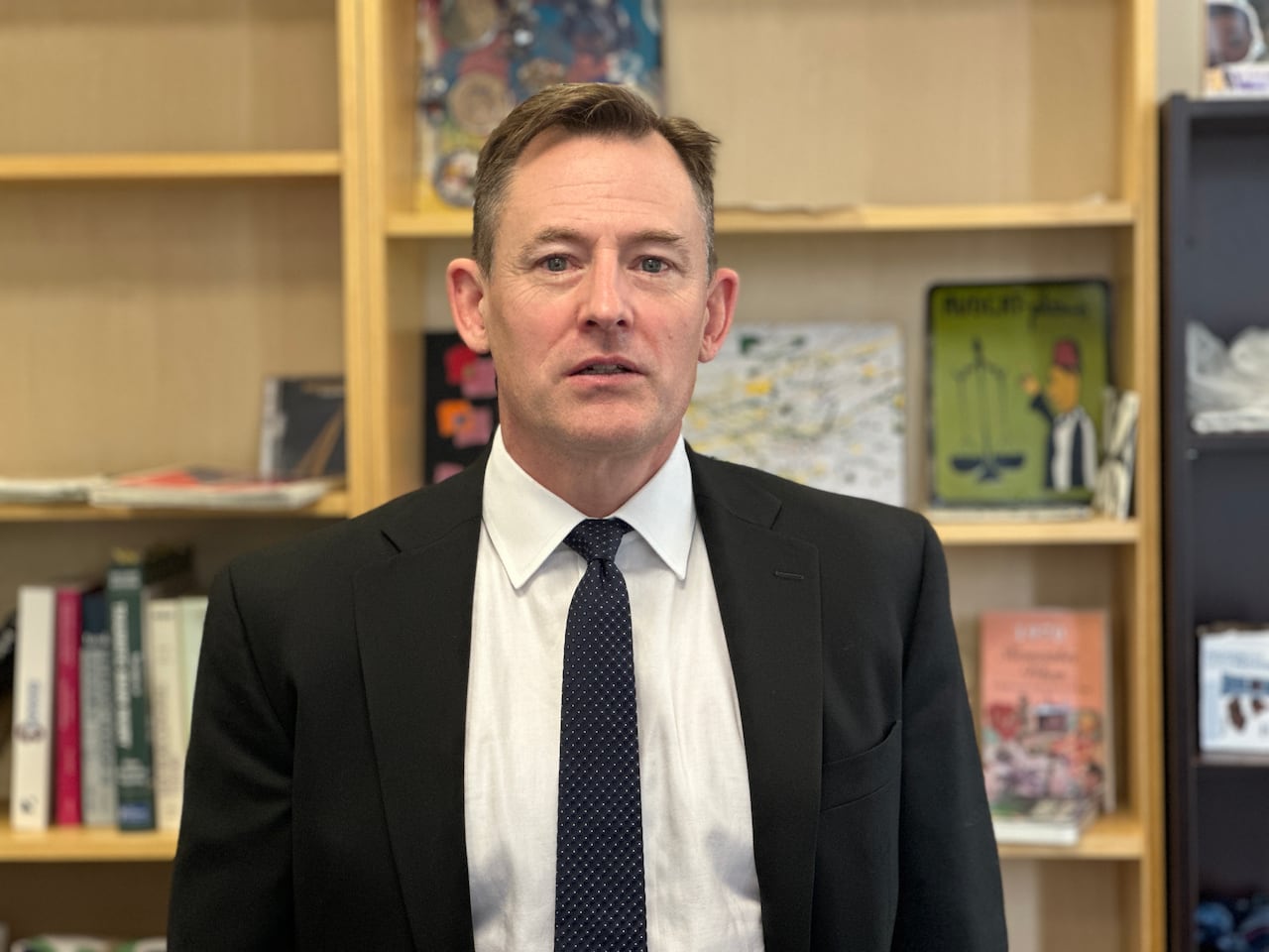 A lawyer stands looking at the camera in a black and white suit.