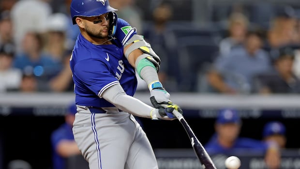 A baseball player dressed in blue hits a ball. 