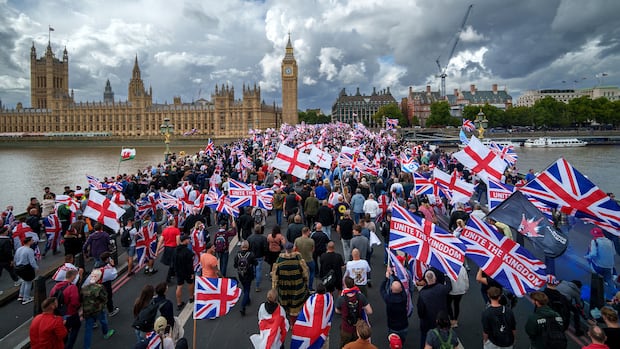 A large crowd of people on a bridge waving flags. 