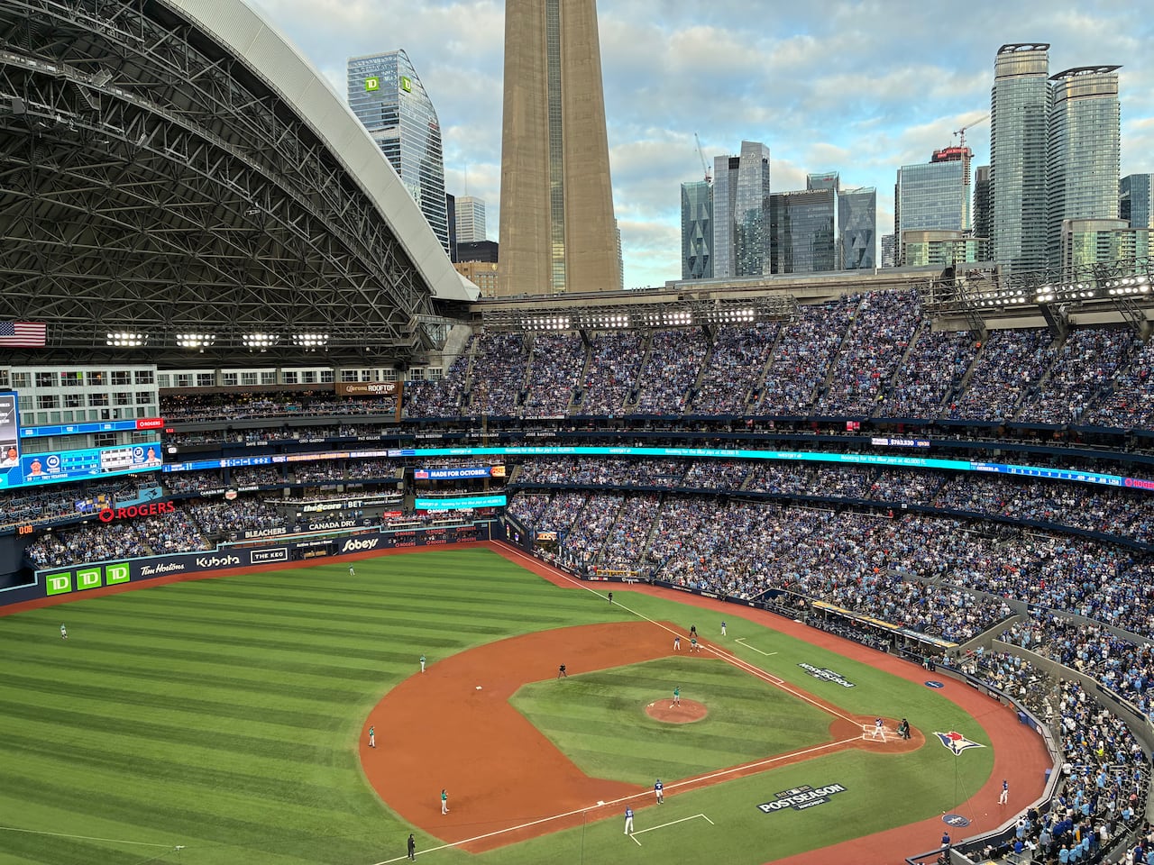 A baseball field is surrounded by thousands of people in stands.
