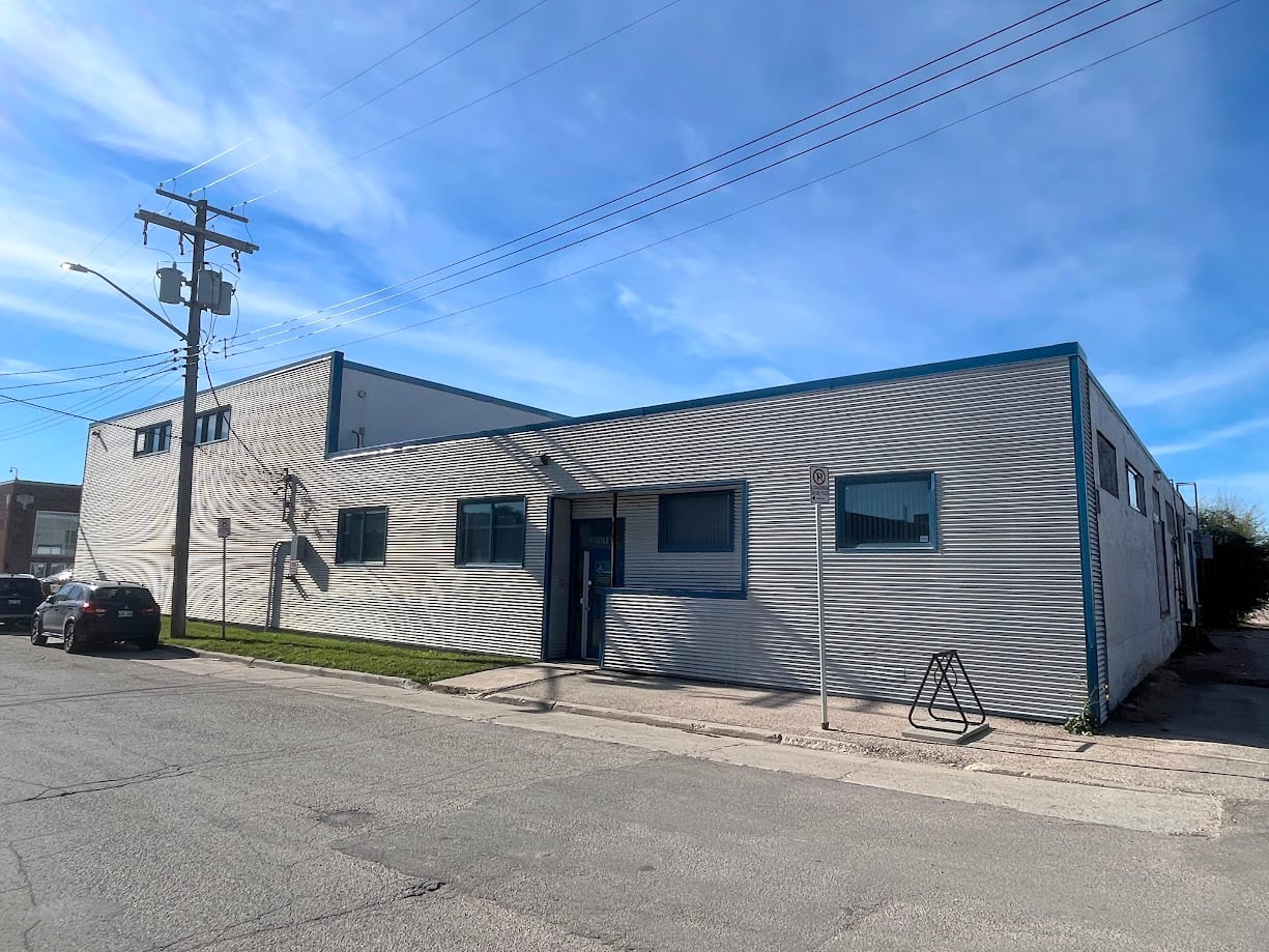 A grey corrugated-metal building is seen from the street