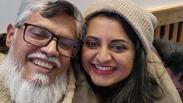 Selfie of father with gray and white hair smiling next to his daughter with black hair.