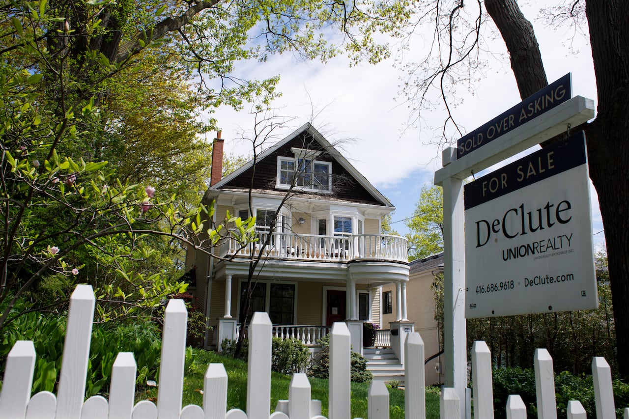 A house is shown with a white picket fence and a real estate sign in the foreground.